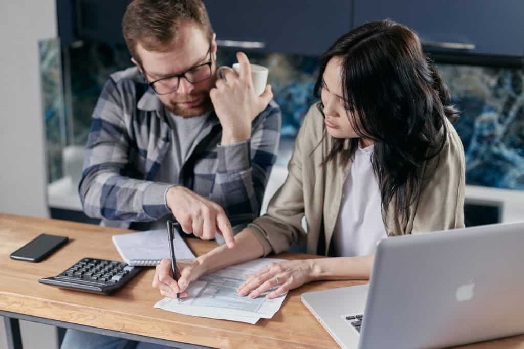 a man and woman sitting at a table looking over pricing sheets for a cleaning cost estimate