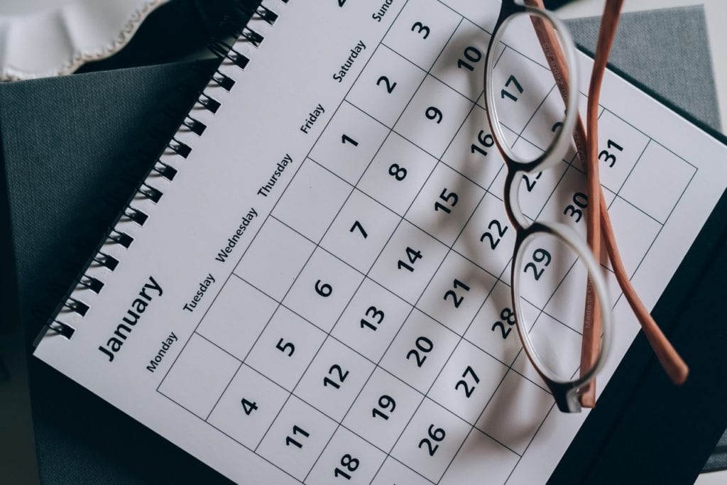 calendar open to January with a pair of glasses laying on top while business sets a cleaning schedule